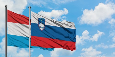 Luxembourg and Slovenia flag waving in the wind against white cloudy blue sky together. Diplomacy concept, international relations.