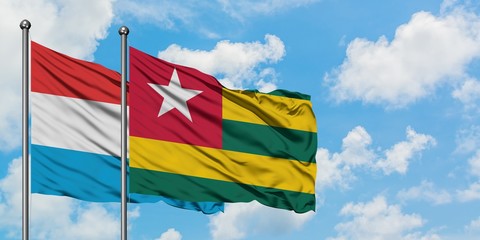 Luxembourg and Togo flag waving in the wind against white cloudy blue sky together. Diplomacy concept, international relations.