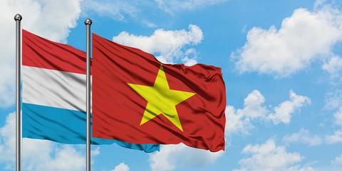 Luxembourg and Vietnam flag waving in the wind against white cloudy blue sky together. Diplomacy concept, international relations.