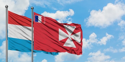 Luxembourg and Wallis And Futuna flag waving in the wind against white cloudy blue sky together. Diplomacy concept, international relations.