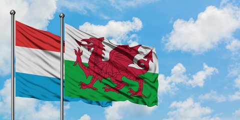 Luxembourg and Wales flag waving in the wind against white cloudy blue sky together. Diplomacy concept, international relations.