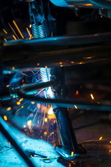 Fototapeta na wymiar Worker welding a motorcycle metal part in gloves. Freeze motion sparks , close-up.