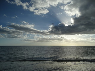 Obraz premium dramatic sun and clouds overcalm ocean water in florida