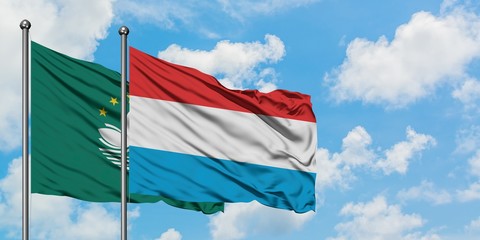Macao and Luxembourg flag waving in the wind against white cloudy blue sky together. Diplomacy concept, international relations.
