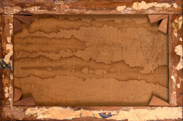 Back of old canvas in wooden frame with remnants of glued newspaper as abstract background