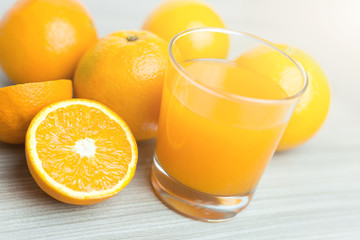 Fototapeta na wymiar Glass of squeezed orange juice. Fresh and juicy oranges on the wooden table.
