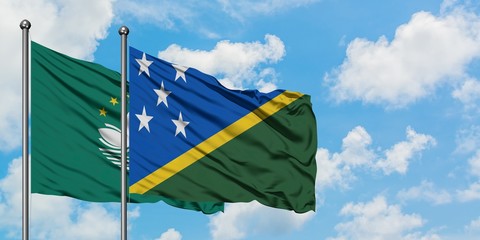 Macao and Solomon Islands flag waving in the wind against white cloudy blue sky together. Diplomacy concept, international relations.