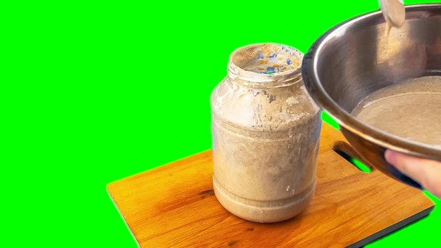 preparing bread . stir the rye sourdough with a spoon in the jar . chromakey mock up closeup green screen background