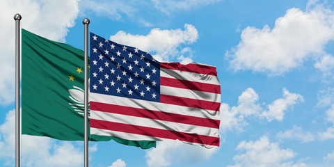 Macao and United States flag waving in the wind against white cloudy blue sky together. Diplomacy concept, international relations.