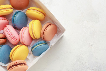 Box with different tasty macarons on white background