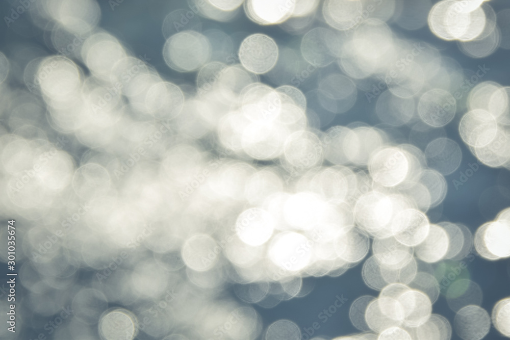 Fototapete Abstract bokeh light background of a defocused river surface with a bokeh effect, reflection of sun glare from water