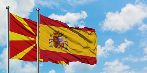 Macedonia and Spain flag waving in the wind against white cloudy blue sky together. Diplomacy...