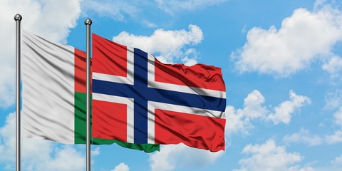 Madagascar and Bouvet Islands flag waving in the wind against white cloudy blue sky together....