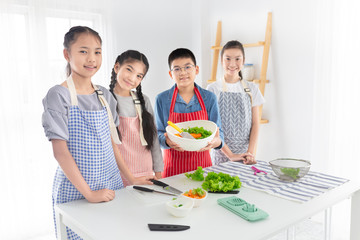 asian children group cooking organic vegetables salad, they holding vegetables with hand, child health nutrition and development promotion, they feeling happy in cooking learning time