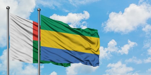 Madagascar and Gabon flag waving in the wind against white cloudy blue sky together. Diplomacy concept, international relations.