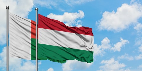 Madagascar and Hungary flag waving in the wind against white cloudy blue sky together. Diplomacy concept, international relations.