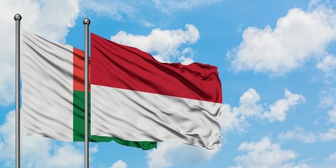 Madagascar and Indonesia flag waving in the wind against white cloudy blue sky together. Diplomacy concept, international relations.