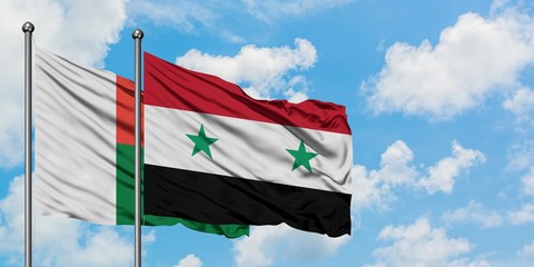 Madagascar and Syria flag waving in the wind against white cloudy blue sky together. Diplomacy concept, international relations.