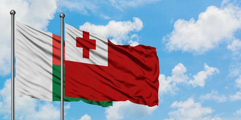 Madagascar and Tonga flag waving in the wind against white cloudy blue sky together. Diplomacy concept, international relations.