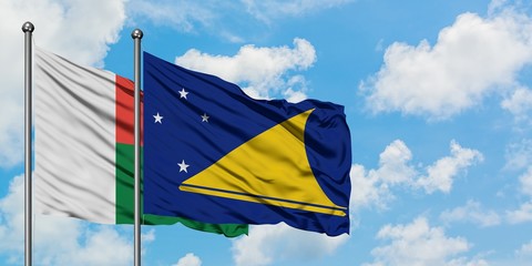 Madagascar and Tokelau flag waving in the wind against white cloudy blue sky together. Diplomacy concept, international relations.