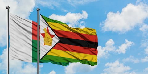 Madagascar and Zimbabwe flag waving in the wind against white cloudy blue sky together. Diplomacy concept, international relations.