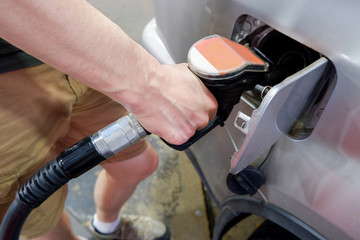 A man hand holding pump filling gasoline. Pumping petrol into the tank. A car refuel on gas station