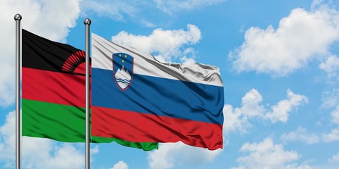 Malawi and Slovenia flag waving in the wind against white cloudy blue sky together. Diplomacy concept, international relations.