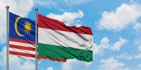 Malaysia and Hungary flag waving in the wind against white cloudy blue sky together. Diplomacy concept, international relations.