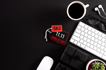 Obraz na płótnie Canvas Online shopping of China, 11.11 singles day sale concept. Red paper tag with keyboard mouse coffee cup, gift box and earphone on black background with copy space for text 11.11 singles day sale.