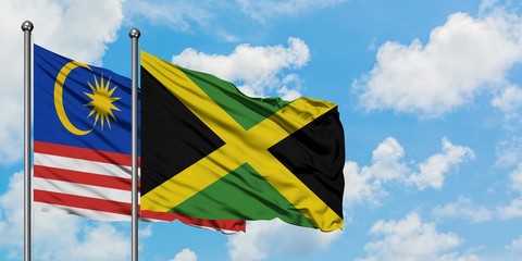 Malaysia and Jamaica flag waving in the wind against white cloudy blue sky together. Diplomacy concept, international relations.