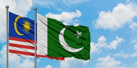 Malaysia and Pakistan flag waving in the wind against white cloudy blue sky together. Diplomacy concept, international relations.