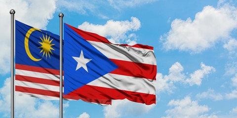 Malaysia and Puerto Rico flag waving in the wind against white cloudy blue sky together. Diplomacy concept, international relations.