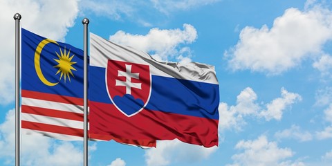 Malaysia and Slovakia flag waving in the wind against white cloudy blue sky together. Diplomacy concept, international relations.