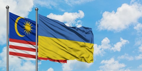 Malaysia and Ukraine flag waving in the wind against white cloudy blue sky together. Diplomacy concept, international relations.