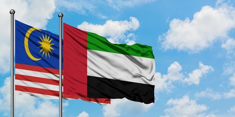 Malaysia and United Arab Emirates flag waving in the wind against white cloudy blue sky together. Diplomacy concept, international relations.