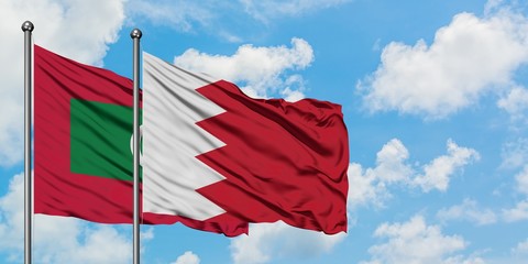 Maldives and Bahrain flag waving in the wind against white cloudy blue sky together. Diplomacy concept, international relations.