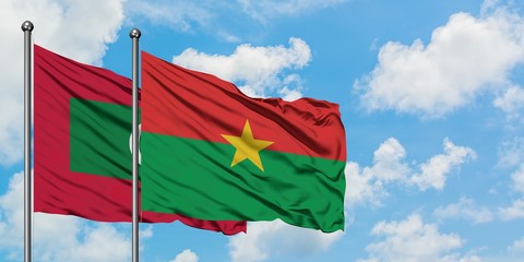 Maldives and Burkina Faso flag waving in the wind against white cloudy blue sky together. Diplomacy...