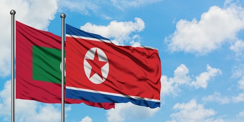 Maldives and North Korea flag waving in the wind against white cloudy blue sky together. Diplomacy concept, international relations.