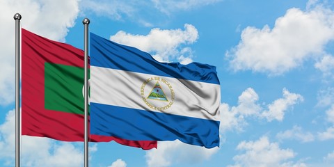 Maldives and Nicaragua flag waving in the wind against white cloudy blue sky together. Diplomacy concept, international relations.