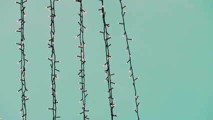 Strands of Christmas Lights Askew against a Solid Turquoise Background