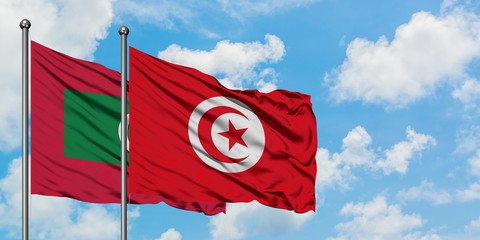Maldives and Tunisia flag waving in the wind against white cloudy blue sky together. Diplomacy concept, international relations.