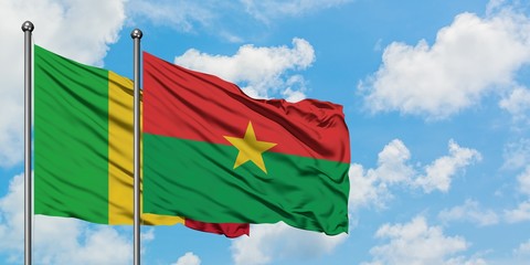 Mali and Burkina Faso flag waving in the wind against white cloudy blue sky together. Diplomacy concept, international relations.