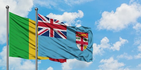 Mali and Fiji flag waving in the wind against white cloudy blue sky together. Diplomacy concept, international relations.