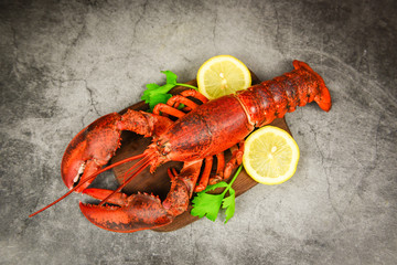 Red lobster with vegetable and lemon on wooden cutting board and black plate background , top view - Lobster dinner