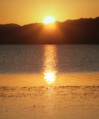 Picturesque sunset on the lake in Mongolia. Bright sun and reflection in the water.