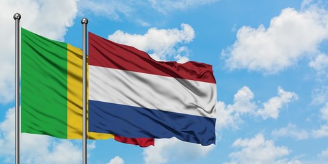 Mali and Netherlands flag waving in the wind against white cloudy blue sky together. Diplomacy concept, international relations.