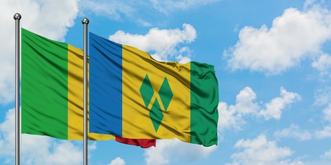 Mali and Saint Vincent And The Grenadines flag waving in the wind against white cloudy blue sky...