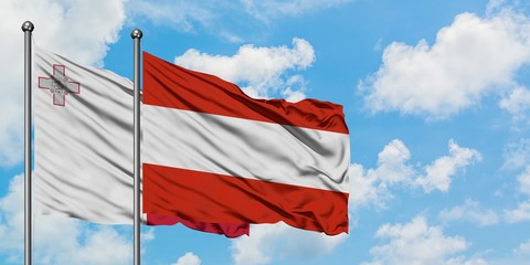 Malta and Austria flag waving in the wind against white cloudy blue sky together. Diplomacy concept, international relations.