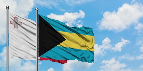 Malta and Bahamas flag waving in the wind against white cloudy blue sky together. Diplomacy concept, international relations.