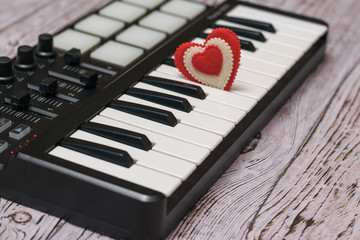 A red heart in the keys of a music mixer on a wooden table.